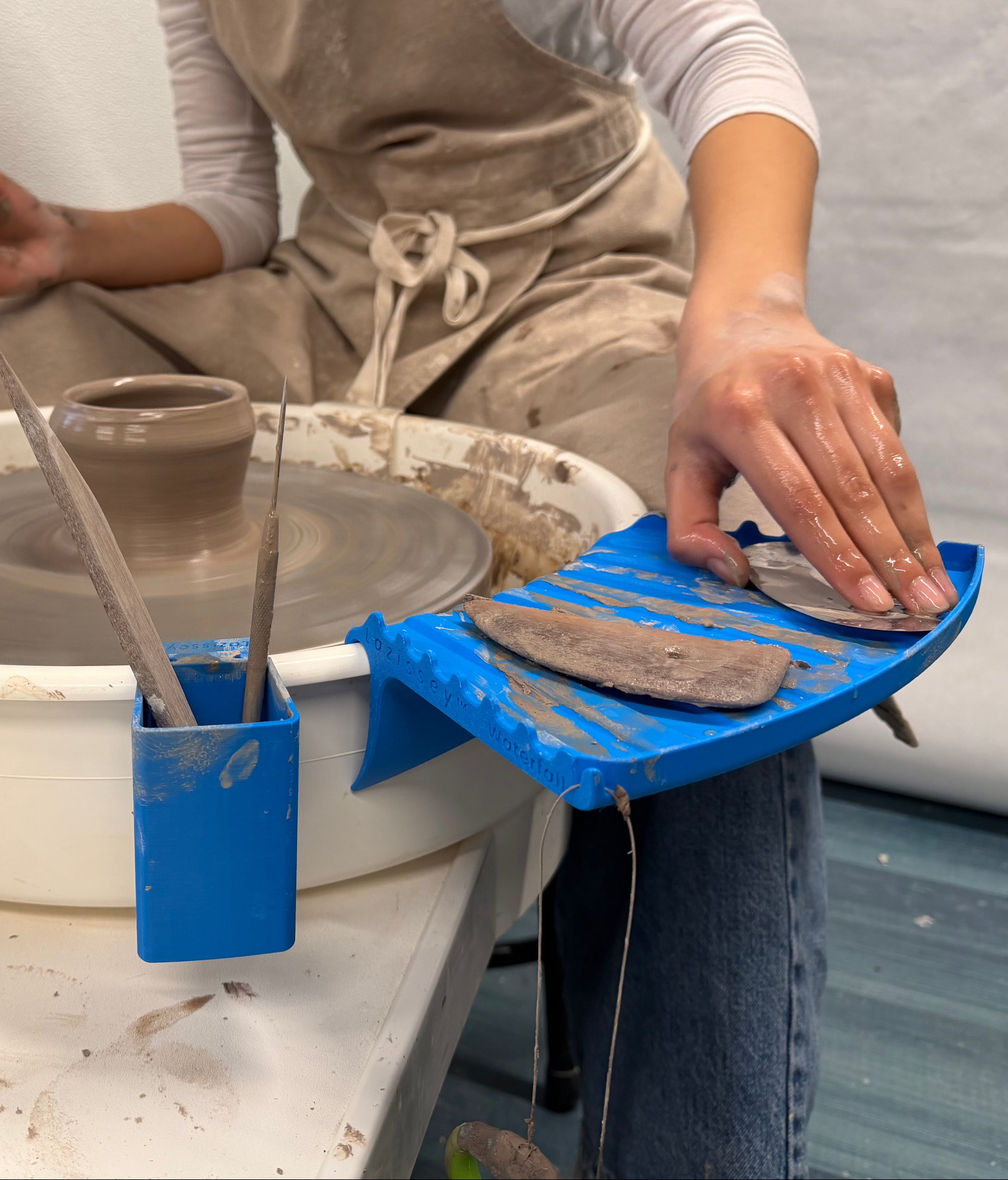 Person working with clay on a pottery wheel in a studio setting